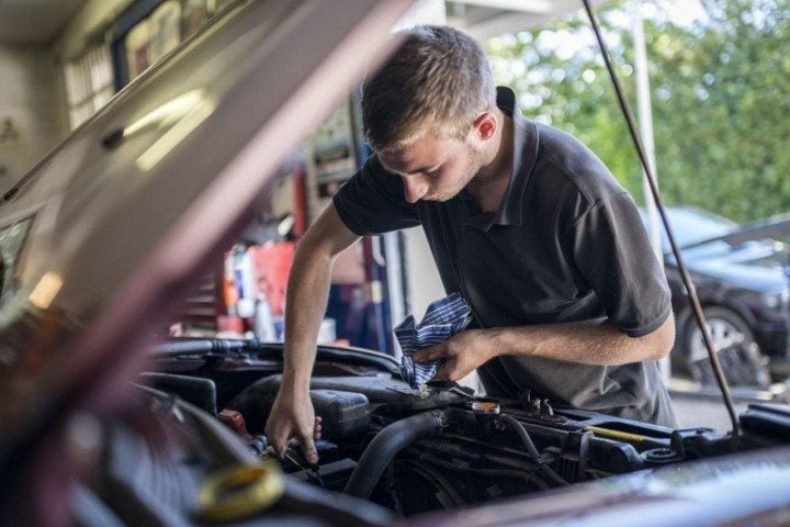 Image of a young man working on car in garage